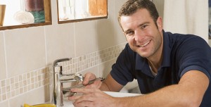 Plumber working on sink smiling